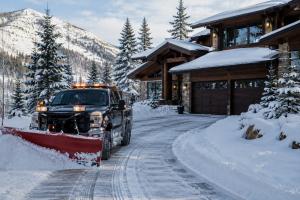 Snow plow removing snow from a mountain modern home