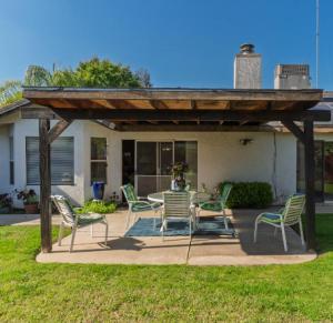 A covered patio with outdoor seating and a dining table overlooking a green lawn at a residential care facility.