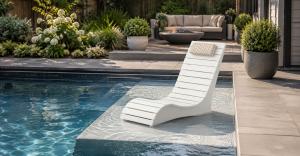 White AquaCurve in-pool lounge chair on a compact shallow sun shelf beside a backyard swimming pool.