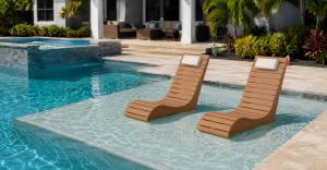 AquaCurve in-pool lounge chairs placed on a shallow water sun shelf in a modern backyard pool.
