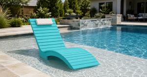 Blue AquaCurve in-pool lounge chair on a shallow tanning ledge beside a residential swimming pool.