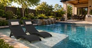 AquaCurve in-pool lounge chairs on a shallow sun shelf in a modern residential backyard pool.