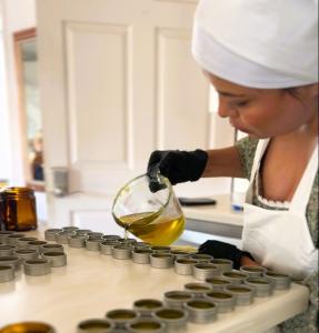 a sister in apron with gloves pouring salve from a glass measuring cup into 1/2 oz tins