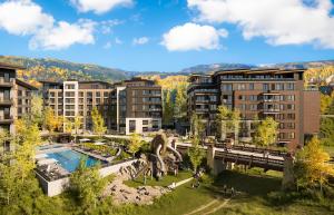 Exterior shot of modern luxury building Stratos Residential Collection in Snowmass, CO. Nestled in the mountains, surrounded by green vibrant trees.