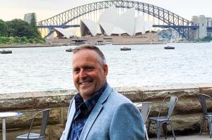 Australian historical novelist Paul Rushworth-Brown photographed at Sydney Harbour with the Sydney Opera House and Harbour Bridge behind him.