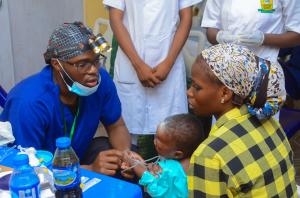A Shekinah Global Volunteer Clinician examines a young child alongside the child's mother at the mission clinic.