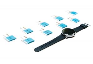 Image showing multiple Silyte anode, 27x27mm smartwatch cells next to a smartwatch to illustrate size.