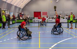 Four wheelchair athletes in red uniforms play doubles pickleball on a blue indoor court at the First Ukrainian Veterans Pickleball Championship in Kyiv, 2026, with the Ukrainian Pickleball Federation banner visible in the background.