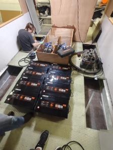A row of black-and-orange LiTime lithium batteries staged inside a boat hull during the ferry's electric powertrain installation.