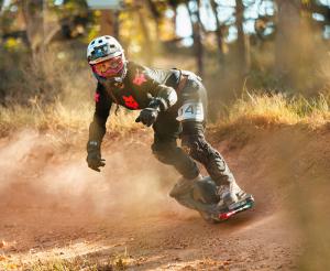 A onewheel racer riding an off-road track leans into a berm