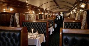 Candlelit tables and a waiter in the wood-paneled dining car of the Rovos Rail Pride of Africa