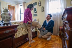 A physical therapists assists an older adult in their home