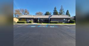 Freshly paved commercial parking lot at a Wells Fargo branch in Santa Rosa with smooth black asphalt, crisp white parking stall lines, two blue ADA-accessible handicap stalls with wheelchair symbols, a center no-parking zone, and the single-story Wells Fa