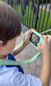 Child using a mint-green Dr.Look Ai Learning Camera at the park for an interactive real-world lesson.