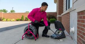Pro Trenchless Services technician performing sewer camera inspection with professional trenchless plumbing equipment outside a commercial building.