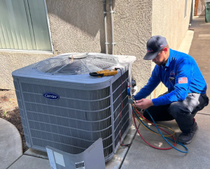 Mechanical Air technician servicing an outdoor Carrier HVAC condensing unit with manifold gauges and diagnostic tools.