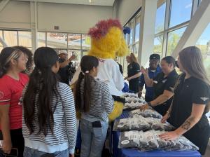 Staff members from Ontario Tower Buzzers, with the assistance of team mascot, Maverick, hand out items to attendees at the Girl's Inc. outreach event.