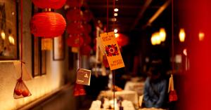 Red lanterns and personalized Map The Room cards hang above a warmly lit restaurant dining area.
