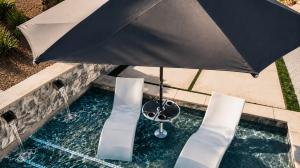 BajaMate luxury in-pool umbrella and table system on a Baja shelf with lounge chairs, designed for resort-style pool shade and swim-up relaxation