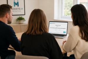 A mediator sits with two clients at a table during a Mediate UK family mediation session, laptop open, using the new legal aid eligibility checker too.
