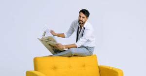Benjamin Aubin, Founder and CEO of VibeBoost, Inc. seated on a yellow sofa holding a newspaper.