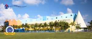 Miami Children's Museum colorful building with palm trees, blue sky, and Certified Autism Center logo in the foreground.