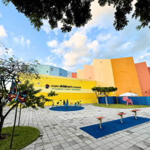 Exterior view of the colorful Miami Children's Museum with playful outdoor sculptures and a blue sky with scattered clouds.