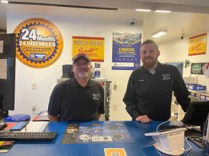Richmond Street Automotive team members at the service counter beneath a NAPA AutoCare 24 month 24,000 mile nationwide warranty sign in Appleton, Wisconsin