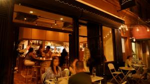 Busy neighborhood restaurant with customers dining inside and outside, representing local businesses participating in the Secret World creator community.