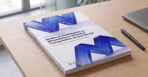 A printed copy of the WeMoral 2026 Report on Whistleblower Directive Transposition Across the EU lying on a desk beside a pen and a laptop.