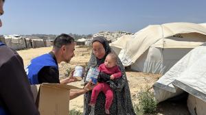 Photo of Life for Relief and Development (LIFE) team member giving a mother in Gaza baby formula.