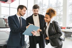 Car dealership employees reviewing a used vehicle with a customer