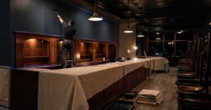 Painter rolling a finish coat on a bar and restaurant interior during overnight off-hours commercial painting work in the Denver metro area
