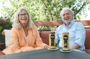 Pharos Brands International co-founders Mary Bernuth and Rhyno Stinchfield seated outdoors with Pharos Premium Infused Beverages.