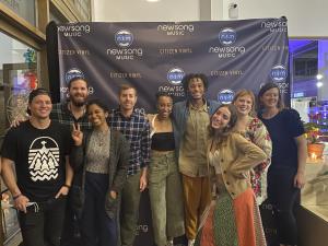 The 2021 NewSong Competition Finalists pose in front of a banner at Citizen Vinyl.