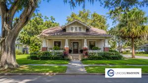 A single-story Craftsman-style bungalow with a covered front porch, brick columns, and a landscaped lawn on a tree-lined street in Lakeland, Florida, with the Lincoln Madison Investments logo in the corner.