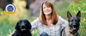 Woman smiling outdoors, sitting between a black dog and a German Shepherd, with a Certified Autism Center badge in the corner.