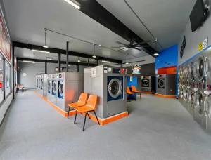 Modern washers, dryers and orange seating inside Sparkle Laundry Lounge in Burbank, CA.