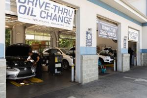 Strickland Brothers drive-thru oil change service bays with technicians working on vehicles beneath signs promoting “10 minutes, zero hassle” service.