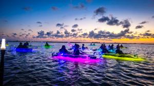 A group of adventure seekers are silhouetted by a magnificent sunset view while on a GlowRow tour