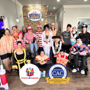 Group of people in colorful costumes posing inside an enrichment center with a welcoming atmosphere.