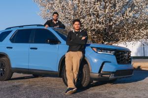 Two Swift Ride team members beside a blue vehicle.
