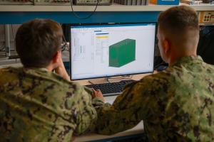 Ensign Justin Williams and Lt. Joshua McCowan demonstrate the Terahertz Imaging Camera (TIC) system’s casing in the space systems lab at NPS. The TIC was one of seven projects selected for the Digital AI Challenge.