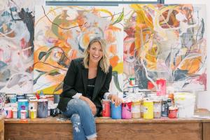 Jodie King, professional artist and educator, sitting in her studio surrounded by paints
