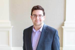 3/4 length photo of Paid Perceptions founder Sam Cohen, in a casual blue and light purple business suit.