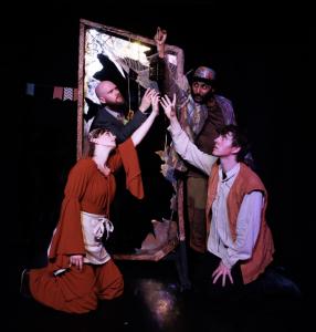 Performers gather around a mirror frame and hanging lantern on stage.