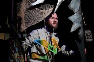 A performer appears amid the surreal stage design of The Inverted Realm.