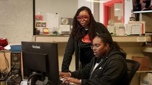 Natasha Broxton and a woman employee working together at a computer inside an automotive recycling business.