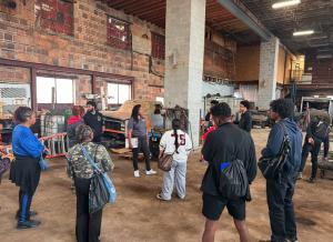 Natasha Broxton speaking with students during a workforce tour inside an automotive recycling warehouse.