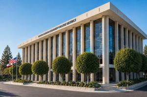 Exterior of the Rancho Santiago Community College District office in Santa Ana, with landscaped grounds and U.S. and California flags.